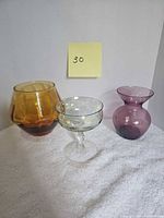Group shot of amber vase, purple vase, green-tinted wine glass