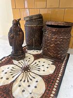 Group view of wood statue, two baskets and batik runner