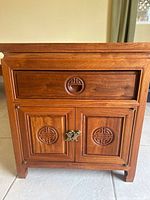 Front view showing drawer, cabinet doors, carvings, hardware