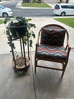 Overall view of chair with cushions beside plant in pot on stand