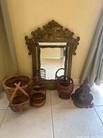 Full view of ornate metal framed wall mirror leaning against wall