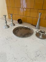 Overall lot showing plate, candlesticks, ladle, bud vase, chamberstick