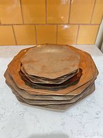 Stack of nine octagonal brass charger plates showing profile and patina variation