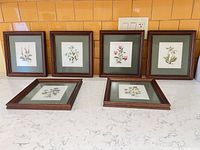 All six framed cross-stitch pieces on countertop