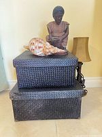 stacked woven rattan boxes, carved figure, conch shell, lamp partially visible