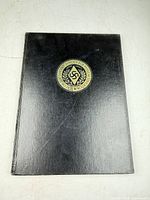 Front cover showing black cloth binding and embossed school seal