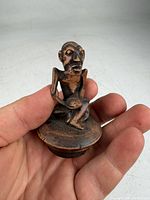 Front view of carved wooden seated old man figurine