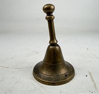 Full view of brass hand bell standing upright