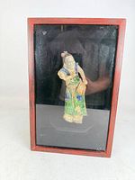Front view of shadowbox displaying ceramic mudman figurine