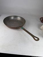 Overall view of copper pan with full handle visible