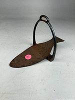 side view of antique iron stirrup showing arched frame and broad foot plate