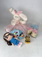 Group shot of all items: plush bunny, crocheted doll, blue plush, snow globe, boxed shoes