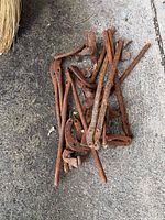 Pile of rusted forged steel tong parts on concrete