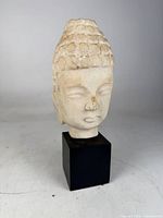 Front view of carved marble Buddha head on base