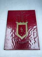 Front cover of red hardcover yearbook with gold crest