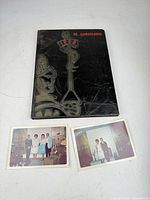 Front cover of yearbook with two loose photographs