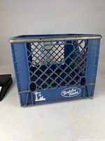 Front view of blue Berkeley Farms milk crate showing logo and lattice design