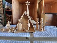 Full nativity scene showing stable, star, five standing figures, three animals and interior figures