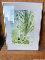 Frontal view of framed watercolor depicting palm trees
