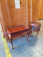 Rectangular side table with pull-out tray beside round display cabinet