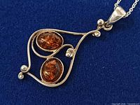 Front view of sterling silver pendant with two amber cabochons on chain