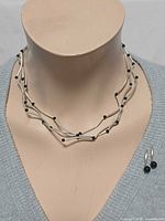 Necklace worn on bust showing design and earrings placed beside