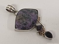 Front view of sterling silver pendant with charoite and accent stones