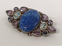 Front view of brooch showing lapis lazuli center and surrounding gemstones