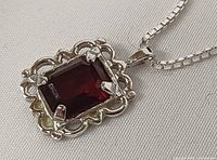 Front view of pendant showing red crystal and ornate silver bezel