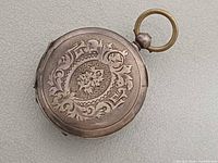 Front view of closed pocket watch showing engraving and bow