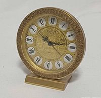 Front view of gold tone Deluxe desk clock showing dial and bezel