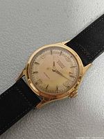 Front view showing dial, hands, gold-tone case