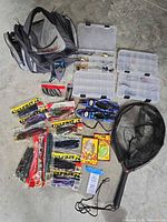 Full lot view showing tackle bag, three tackle boxes, packaged soft baits, tool holsters, net