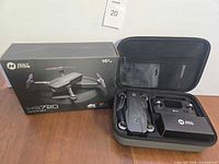 Drone, remote controller, battery pack inside open carrying case beside retail box