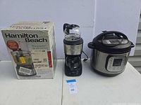 Boxed Hamilton Beach food processor, Farberware coffee maker, Instant Pot pressure cooker grouped together