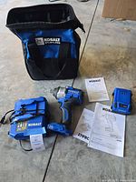 Impact wrench, battery, charger, bag and manuals laid out