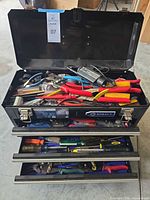 Open chest showing assorted hand tools in top compartment and drawers