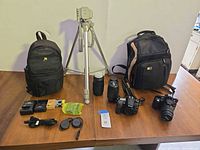 Full lot overview showing cameras, lenses, tripod, bags, chargers, accessories
