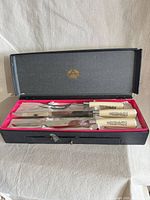 Open box showing carving knife, carving fork and sharpening steel with ivory handles