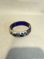 Top view of cloisonné floral bangle showing hinge and enamel design
