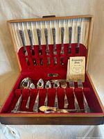 Open wooden chest showing full 57-piece flatware set