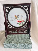 Full view of embroidered panel on stand atop storage box