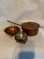 All three copper pieces shown together: saucepan with lid, shallow pan, salt cellar