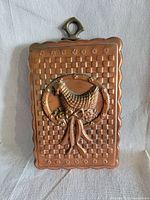 Front view showing copper checkerboard design with raised hen and ribbon