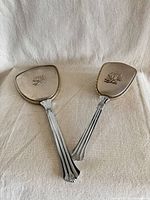 Front view of mirror and brush showing silverplate backs with floral motif and fluted handles
