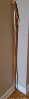 Full view of hand-carved wooden walking stick leaning against wall