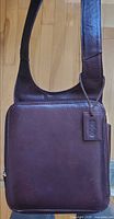 Front view of brown leather crossbody bag showing rectangular body and wide strap