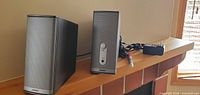 Two Bose Companion 2 Series II speakers with power adapter and cable on shelf