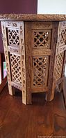 Folding wooden base showing carved lattice panels and hinges