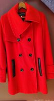 Front view red double-breasted pea coat with black buttons and faux leather pocket trim
